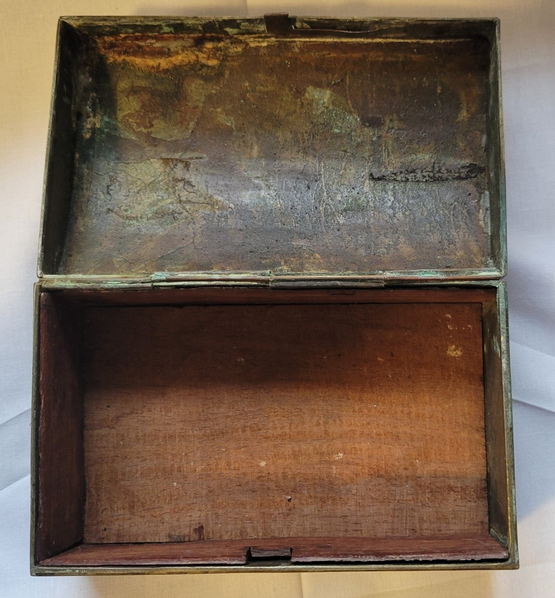 Antique brass box curio made in China, with a domed lid. The interior bottom has wood inserts on three side (one side is missing). The exterior has welded medallions with Chinese characters and designs. View of inside.