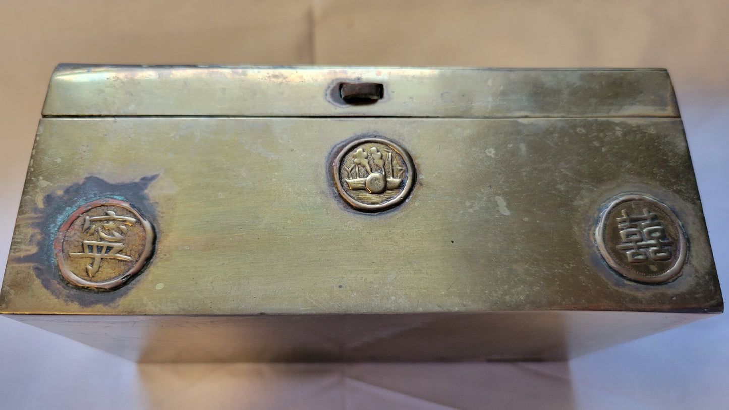 Antique brass box curio made in China, with a domed lid. The interior bottom has wood inserts on three side (one side is missing). The exterior has welded medallions with Chinese characters and designs. View of front.