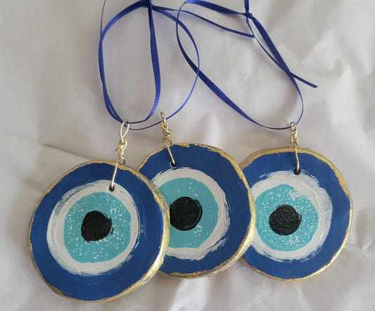 Handmade "Evil Eye" charm ornament.  A popular amulet from the Middle East to protect against the evil eye and curses.  Gifts for history lovers.  Round clay ornament painted with blue eye and hung with a blue ribbon.