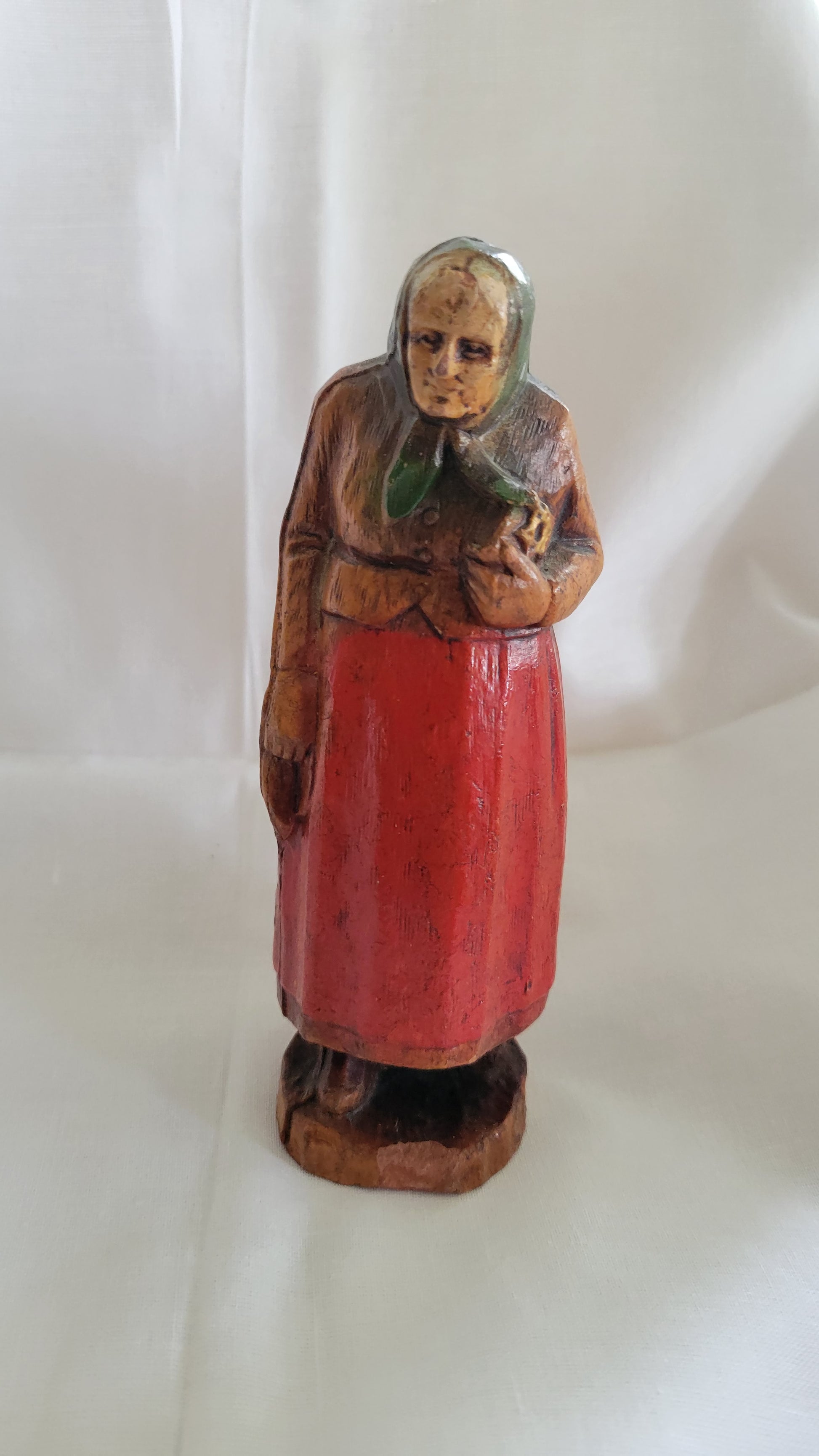 Small Jewish, Yiddish grandmother or Bubbe figure, antique, holding Jewish Bible, possibly SyrocoWood. Front view.