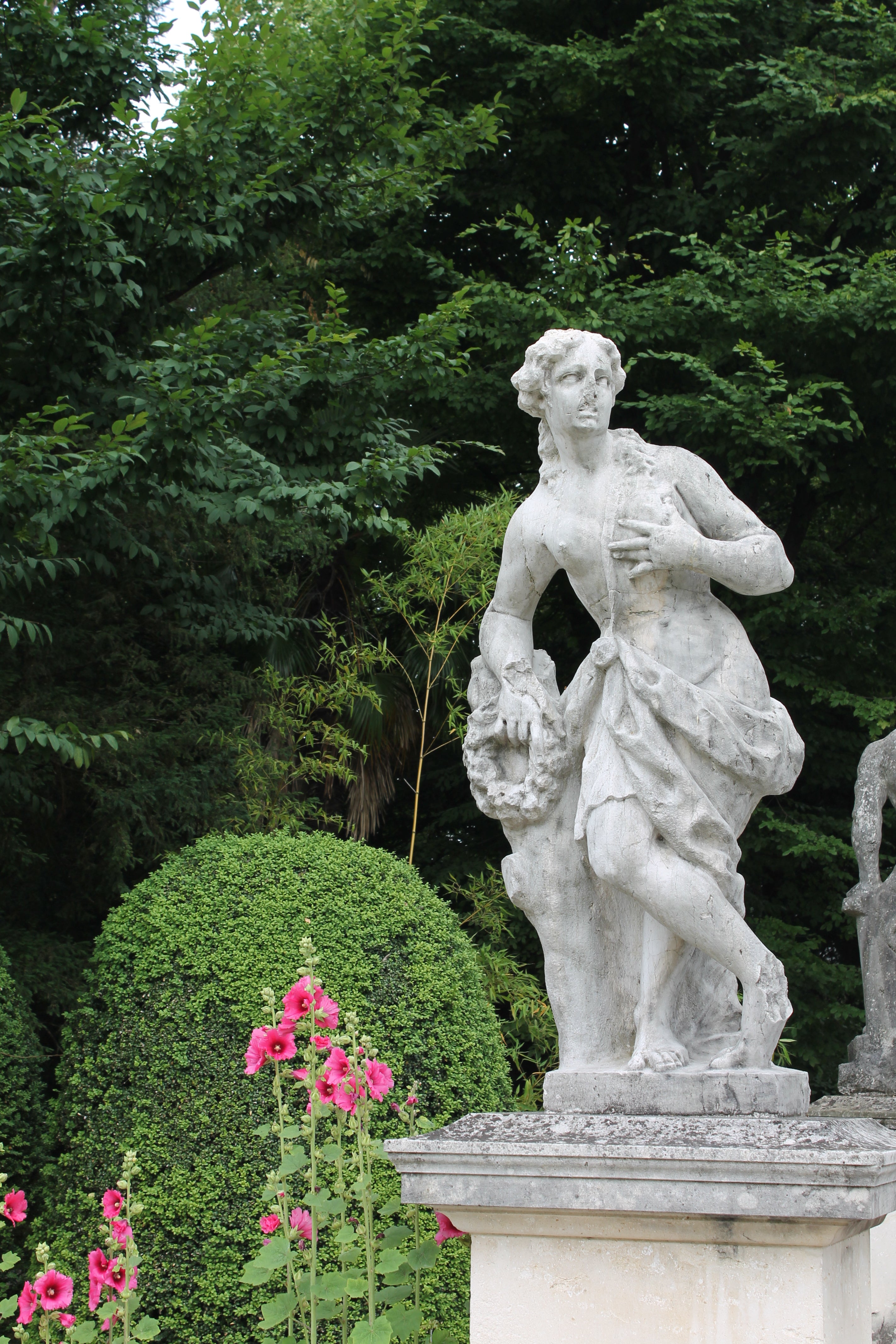 Picture of an ancient statue of a woman from Villa Sandi in Italy, shrubbery behind, for historical consultation page, offering historical research and writing services, Photoshop services, and more.