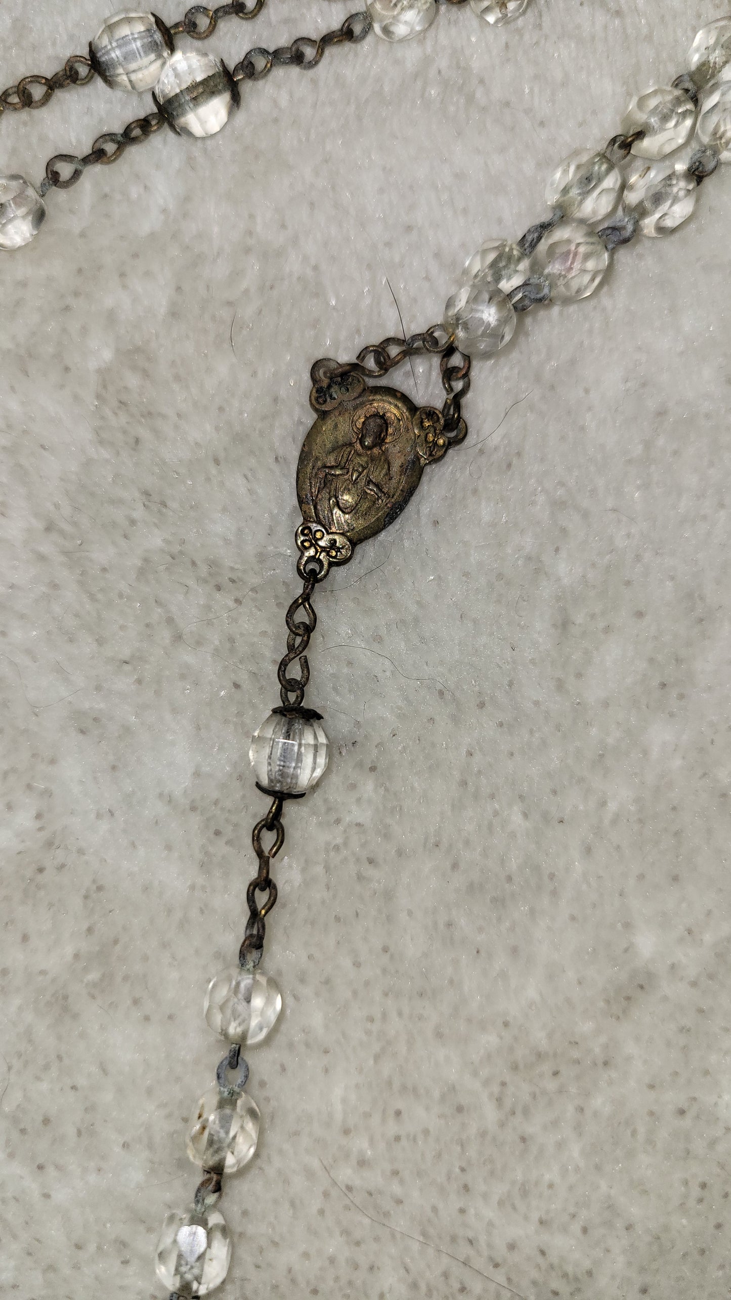 Christian Catholic rosary with crucifix and clear beads. View of medallion 