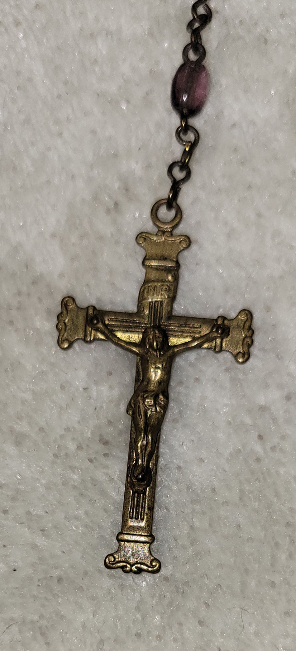 Christian Catholic rosary with crucifix and purple beads. Close-up view of crucifix.