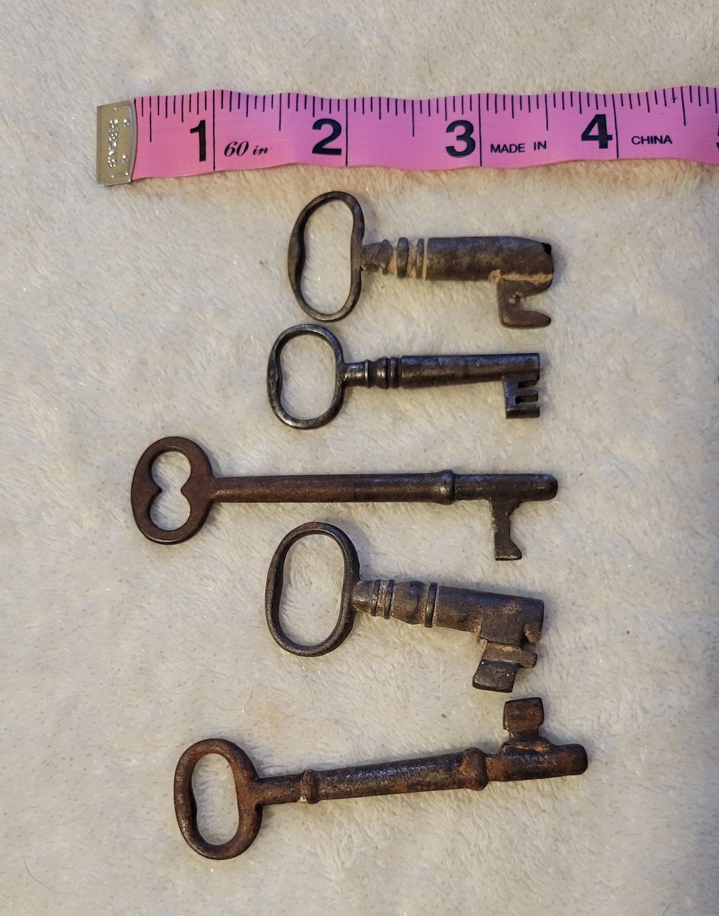 We have a collection of small, metal, antique keys (from which we will pick one for your order).  View of several metal antique, vintage keys.