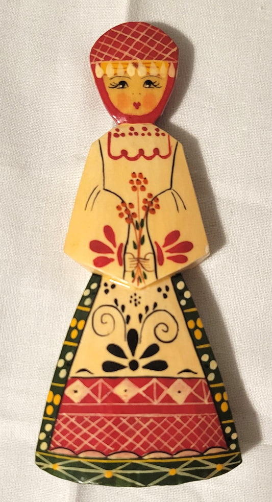 Small wooden doll made in Russia, with traditional dress. Front.