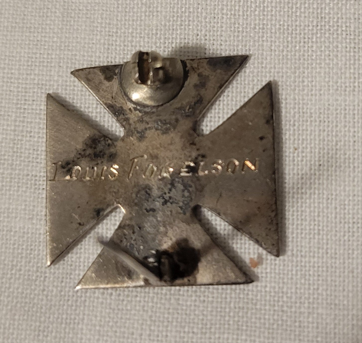 An antique Sunday School cross pin, with "Our Savior" engraved on the front of it. On the back, the name "Louis Fogelson" is engraved. Back view.