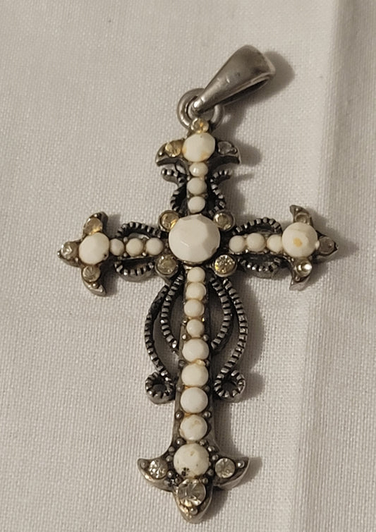 An antique cross pendant with white beads, front view.