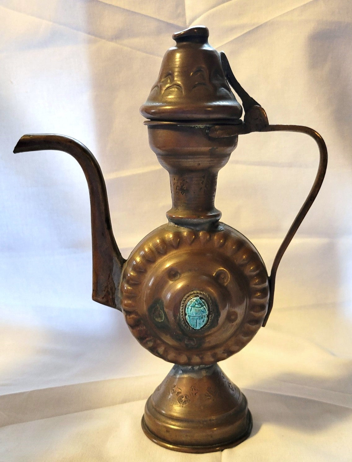 Antique, Egyptian copper kettle with a glazed turquoise scarab beetle on both sides.  The scarab beetle was a symbol of death and rebirth in ancient Egypt. Back view.