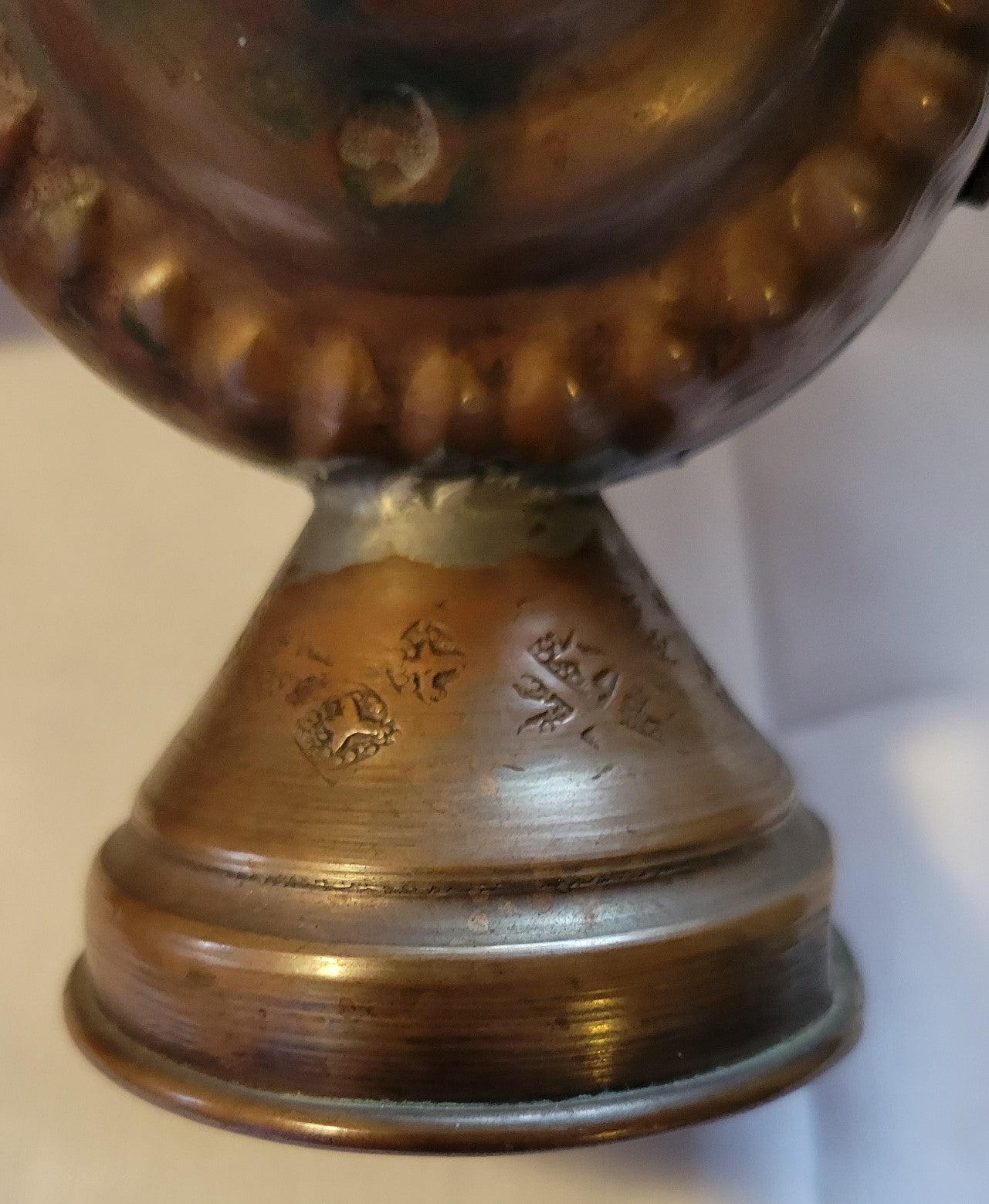 Antique, Egyptian copper kettle with a glazed turquoise scarab beetle on both sides.  The scarab beetle was a symbol of death and rebirth in ancient Egypt. View of details around the base.