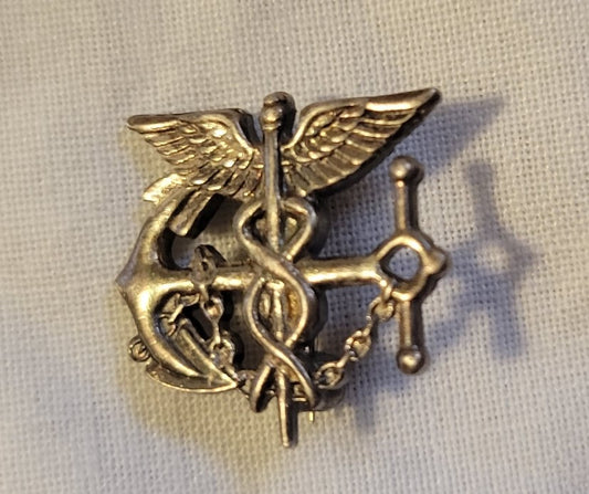 A sterling silver U.S. Public Health Service Commissioned Corps insignia button. Front view.
